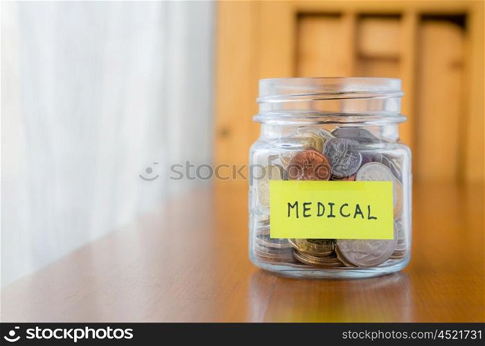 Glass bank with many world coins and medical word or label on saving money jar