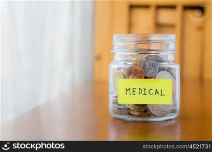 Glass bank with many world coins and medical word or label on saving money jar