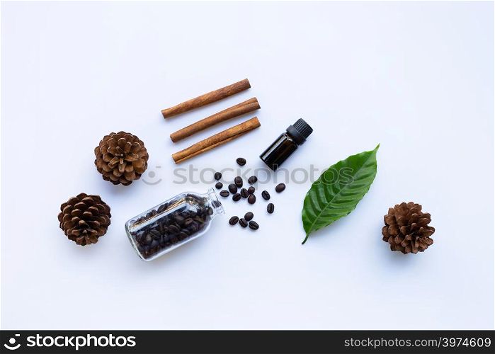Glass bottle of coffee essential oil and cinnamon on white background