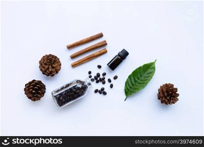 Glass bottle of coffee essential oil and cinnamon on white background