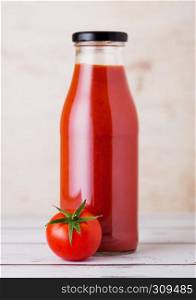 Glass bottle of tomato paste with raw fresh organic tomato on wooden background
