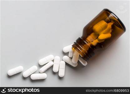 Glass bottle of white pills. Glass bottle of white pills on gray background