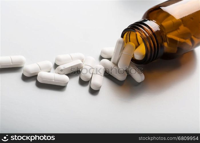 Glass bottle of white pills. Glass bottle of white pills on gray background