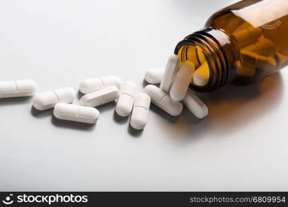 Glass bottle of white pills. Glass bottle of white pills on gray background