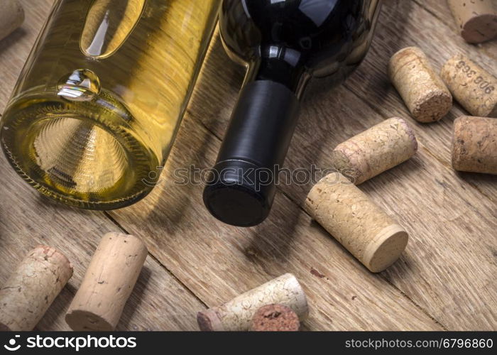 Glass bottle of wine with corks on wooden table background