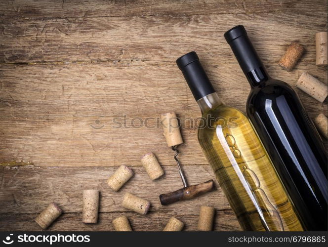 Glass bottle of wine with corks on wooden table background