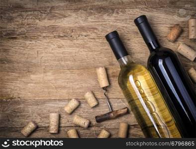 Glass bottle of wine with corks on wooden table background