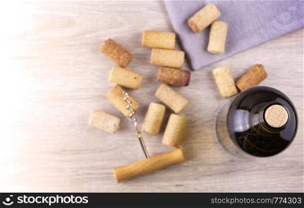 Glass bottle of wine with corks on wooden table background. Top view