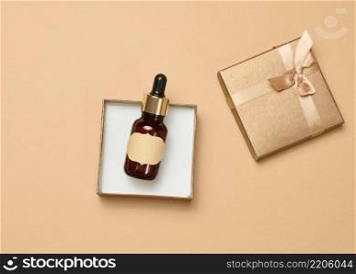 glass bottle with a paper empty label in a box, t top view. Container for cosmetics, aroma oils