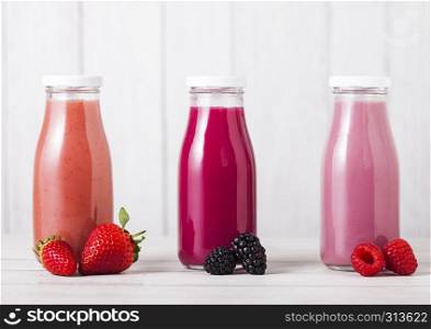 Glass bottle with fresh summer berries smoothie on wooden background.Strwberries and raspberies with blueberries and blackberries.