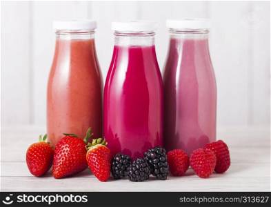 Glass bottle with fresh summer berries smoothie on wooden background.Strwberries and raspberies with blueberries and blackberries.