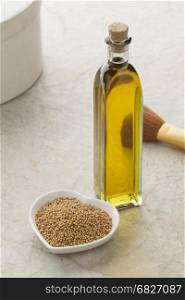 Glass bottle with mustard oil and a dish with seeds for skin care