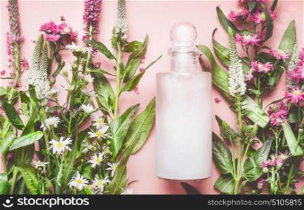 Glass bottle with natural cosmetic product: lotion or shampoo with fresh herbs and flowers on pink background, top view. Beauty, skin, hair or body care concept