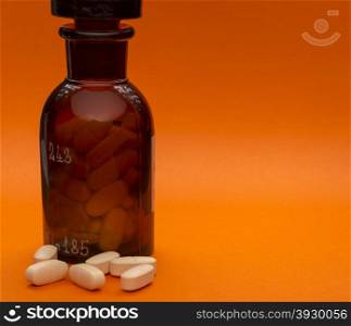 Glass bottle with pills and sopy space on orange background. Glass bottle with pills and sopy space