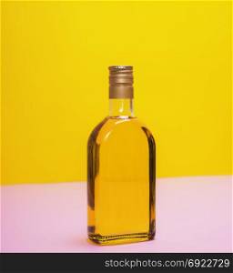 glass bottle with yellow liquid on a yellow background