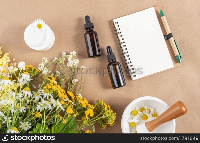 Glass bottles and jar with cosmetic products, bouquet of wild flowers, mortar bowl, open notepad on beige background. Concept natural herbal organic cosmetic, homeopathic cosmetology. Mockup Top view.. Glass bottles and jar with cosmetic products, bouquet of wild flowers, mortar bowl, open notepad on beige background. Concept natural herbal organic cosmetic, homeopathic cosmetology. Mockup Top view