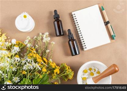 Glass bottles and jar with cosmetic products, bouquet of wild flowers, mortar bowl, open notepad on beige background. Concept natural herbal organic cosmetic, homeopathic cosmetology. Mockup Top view.. Glass bottles and jar with cosmetic products, bouquet of wild flowers, mortar bowl, open notepad on beige background. Concept natural herbal organic cosmetic, homeopathic cosmetology. Mockup Top view