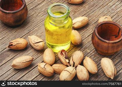 Glass bottles with natural pecan oil with nuts. Unpeeled pecans nut