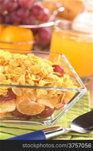 Glass bowl full of fresh fruits (banana, apple, mandarin, grapes) with corn flake cereal (Selective Focus, Focus one third into the corn flakes)