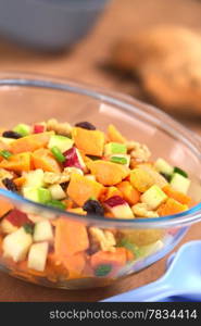 Glass bowl of fresh salad made of cooked sweet potatoes, fresh apples, nuts, raisins and shallots (Selective Focus, Focus one third into the salad). Sweet Potato and Apple Salad