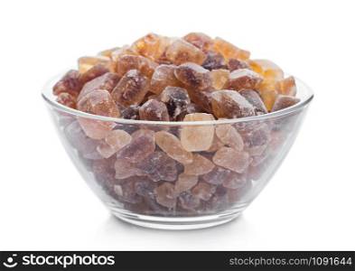Glass bowl of natural brown caramelized sugar cubes on white.