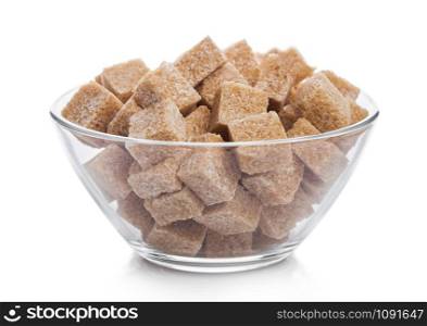 Glass bowl of natural brown sugar cubes on white.