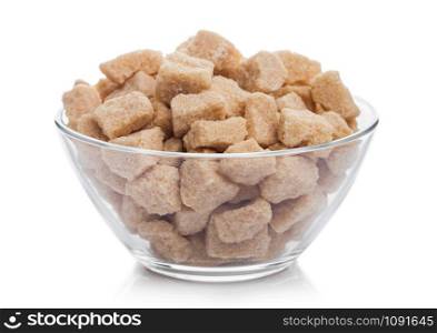 Glass bowl of natural brown unrefined sugar cubes on white.