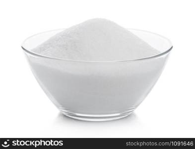 Glass bowl of natural white refined sugar on white.