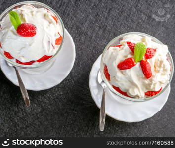 Glass bowl of strawberries with whipped cream. Two bowls with strawberries and whipped cream