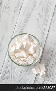 Glass bowl of white lump sugar on the wooden background