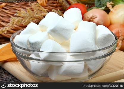 Glass bowl of white marshmallows in kitchen.