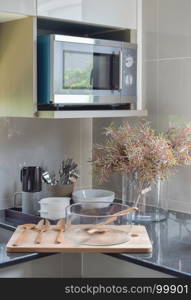 Glass bowl with wooden utensil on wooden tray in the kitchen