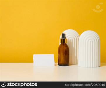 glass brown bottle with cosmetic spray on a yellow background