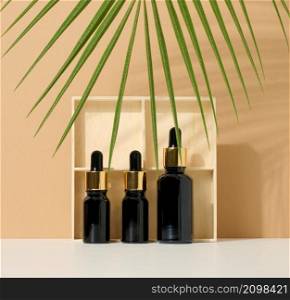 glass brown bottle with pipette on light brown background, palm leaf. Mockup skincare cosmetic product