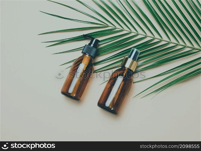 glass brown cosmetic bottles with spray and dispenser on a gray background, top view. Containers for liquid products