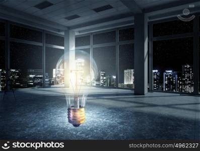 Glass bulb in interior. Glowing light bulb in modern night office