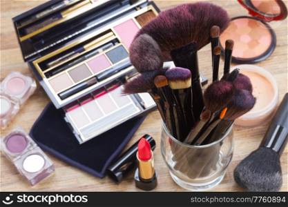glass can with brushes and make up products on wooden table. can with brushes
