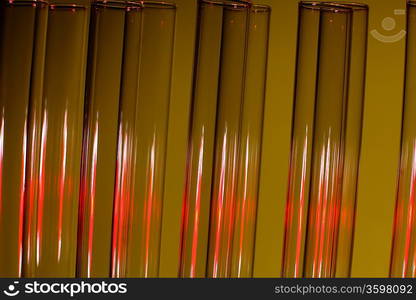 Glass chemistry tubes on a colour background