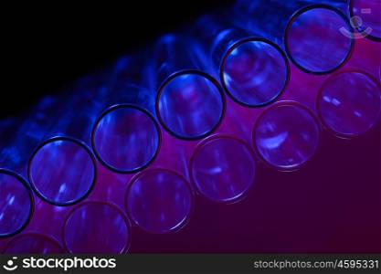 Glass chemistry tubes on a colour background