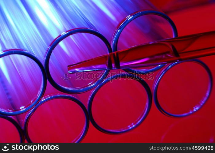 Glass chemistry tubes on a colour background