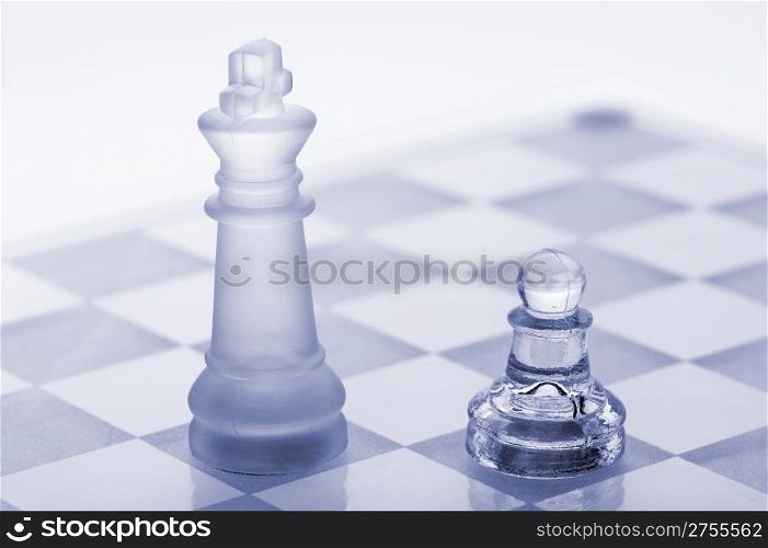 Glass chess. A pawn and a king. Blue toned. It is isolated on a white background.