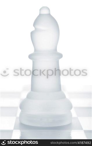 glass chess bishop is standing on board, cut out from white background