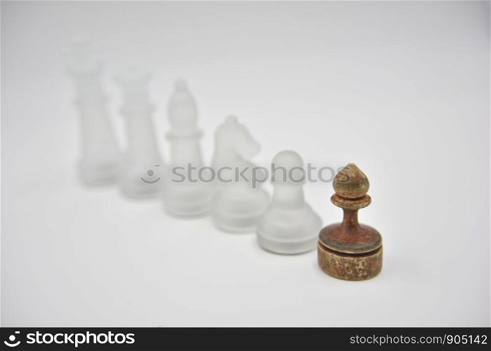 glass chess figures behind wooden ponce on white background