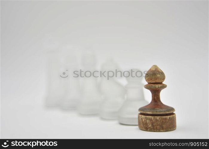 glass chess figures behind wooden ponce on white background