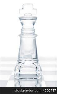 glass chess king is standing on board, cut out from white background