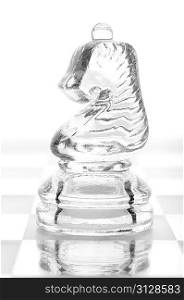 glass chess knight is standing on board, cut out from white background