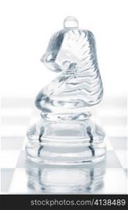 glass chess knight is standing on board, cut out from white background