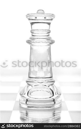 glass chess queen is standing on board, cut out from white background