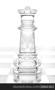 glass chess queen is standing on board, cut out from white background