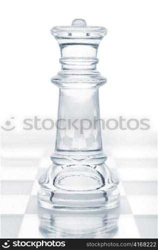 glass chess queen is standing on board, cut out from white background